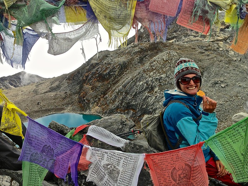 Lina surrounded by prayer flags, enjoying a cookie on Kongma La Pass Lina surrounded by prayer flags, enjoying a cookie on Kongma La Pass